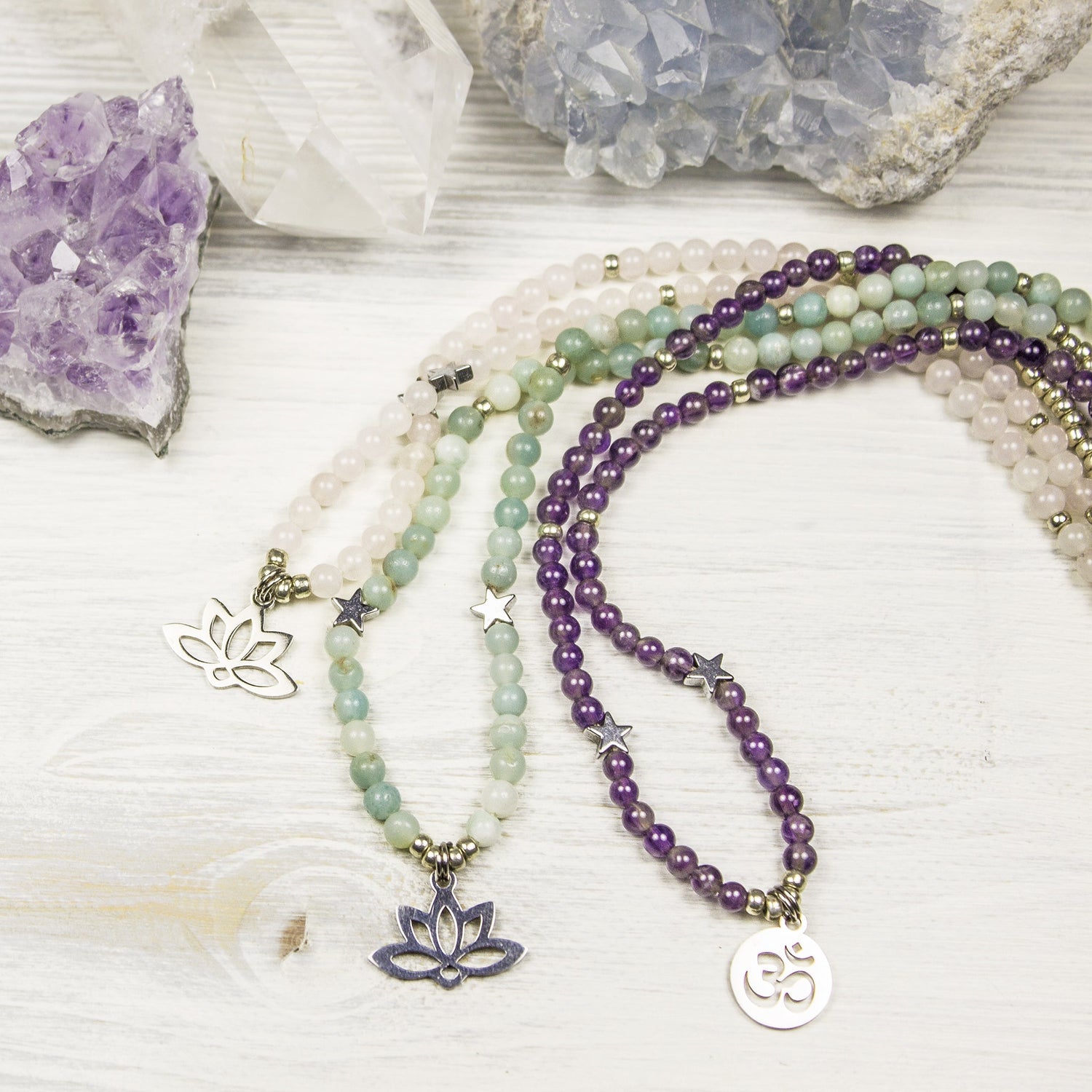 Three gemstone necklaces on a wood background with crystals
