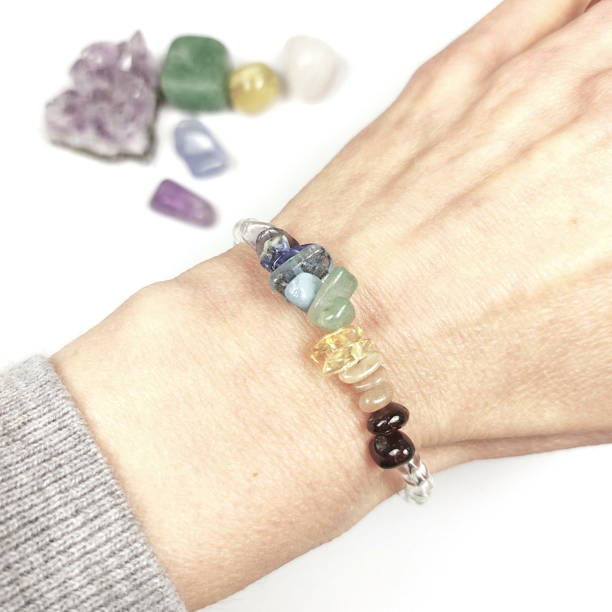Multicolored beaded crystal bracelet on a wrist with crystals in the background